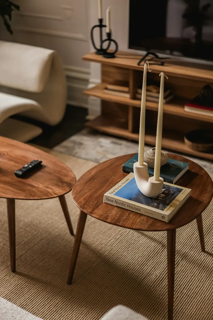 Wooden coffee tables beside a pale armchair, with candles arranged on the table.